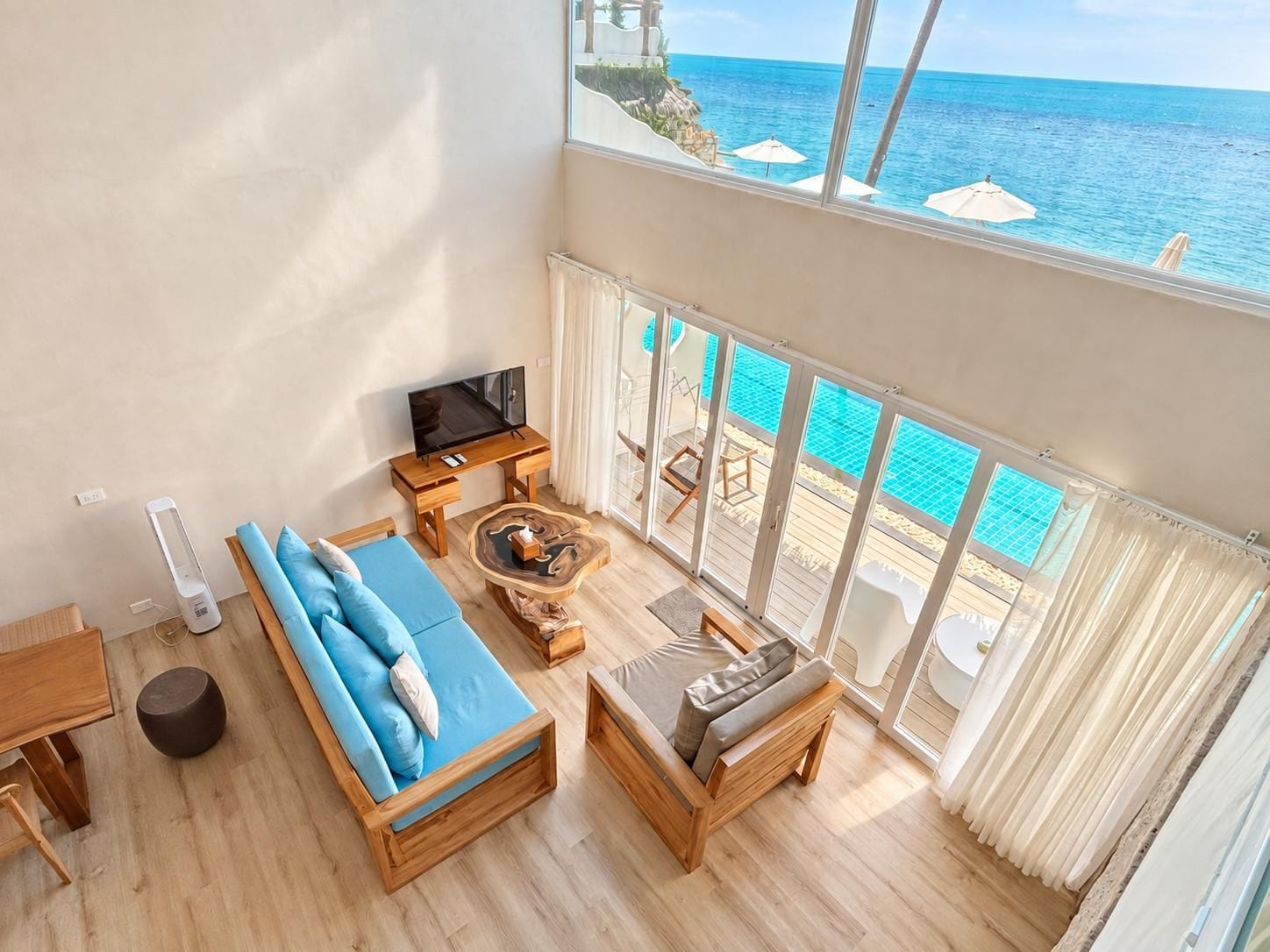 Un ampio balcone con vista sull'oceano, arredato con un divano, un tavolino da caffè e una televisione.