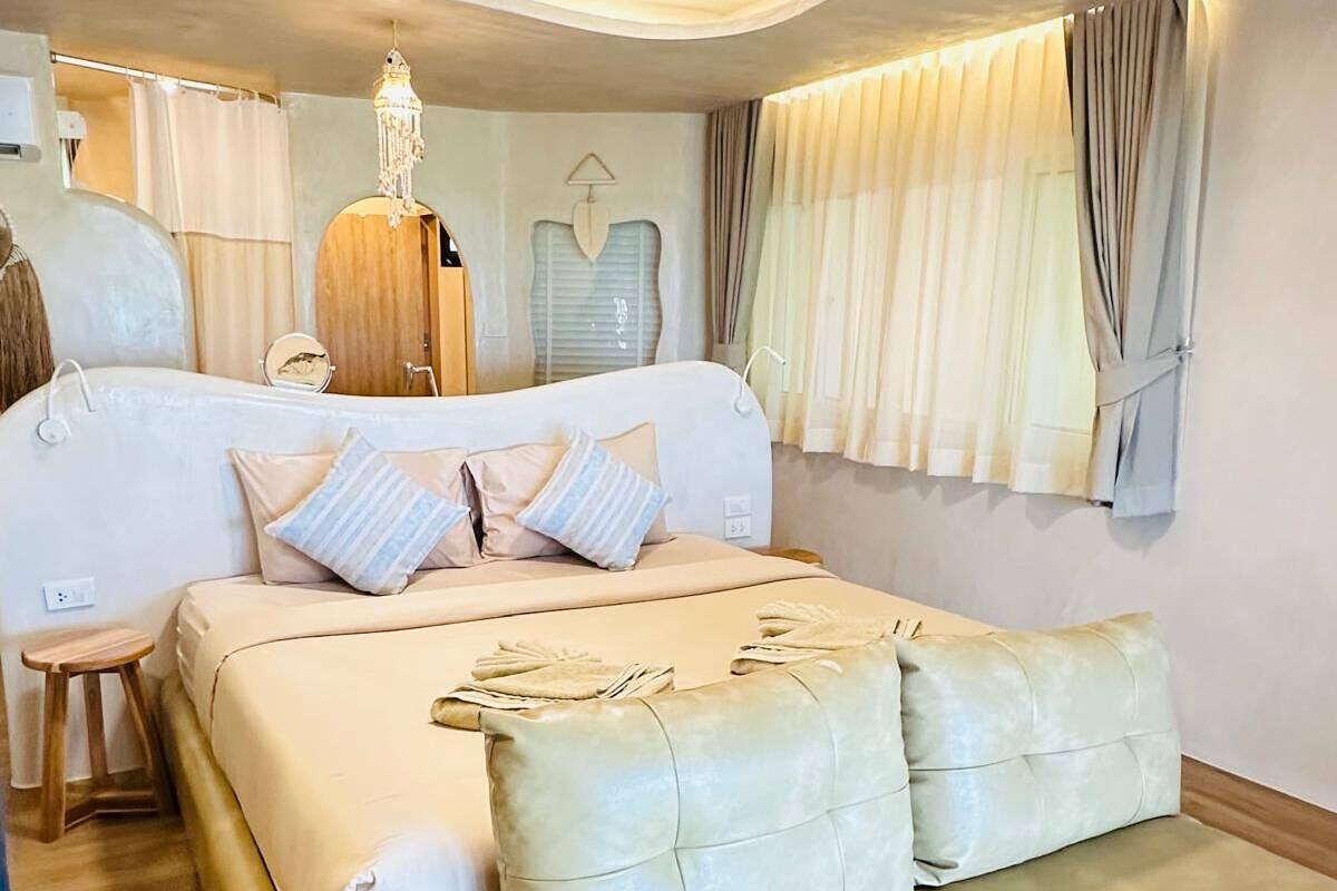 Une chambre à coucher comprenant un lit, un banc, un ventilateur de plafond et un luminaire suspendu.