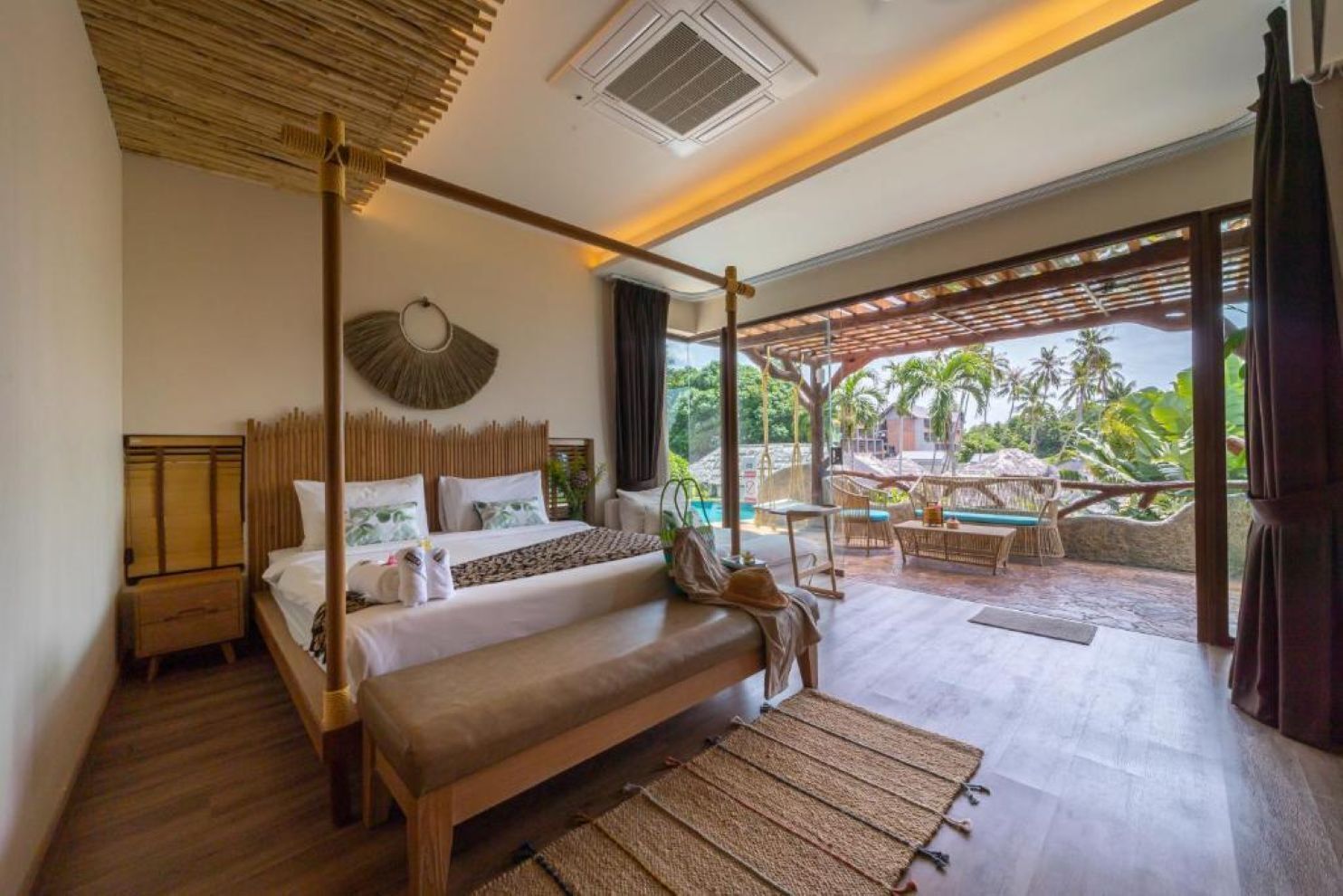 Een slaapkamer met een bed, nachtkastjes, een bankje en uitzicht op het omliggende landschap.