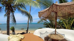 Eine Strandlounge mit Meerblick, einer Hängematte und einem gewebten Sonnenschirm.