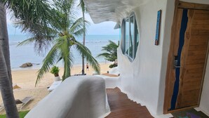 Blick auf einen Strand von einer überdachten Veranda mit einer Holzt ür und einer Treppe, ein Schild zeigt das Wort 'Sweet'.
