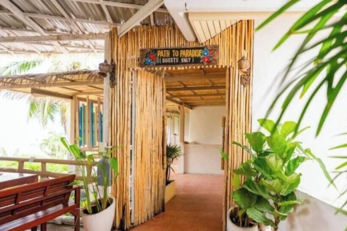 Une entrée en bambou sur laquelle est affiché un panneau indiquant : « Chemin vers le paradis (réservé aux clients) ».