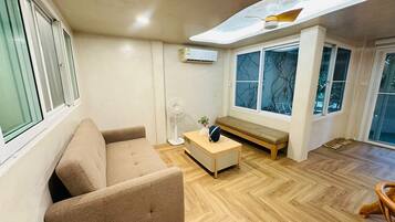 A modern living room with a sofa, a wooden coffee table, a bench, and a ceiling fan.