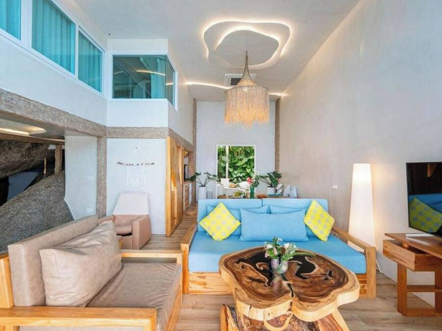 A modern living room with a blue sofa, wooden coffee table, and a chandelier.