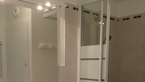 A bathroom with a white sink, mirror, and glass shower enclosure.