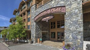 Un hotel de varios pisos con fachada de piedra y un llamativo logo con un águila.