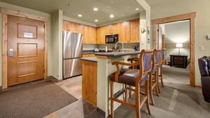 Una cocina moderna con armarios de madera, electrodomésticos de acero inoxidable y una zona de bar con sillas de cuero.