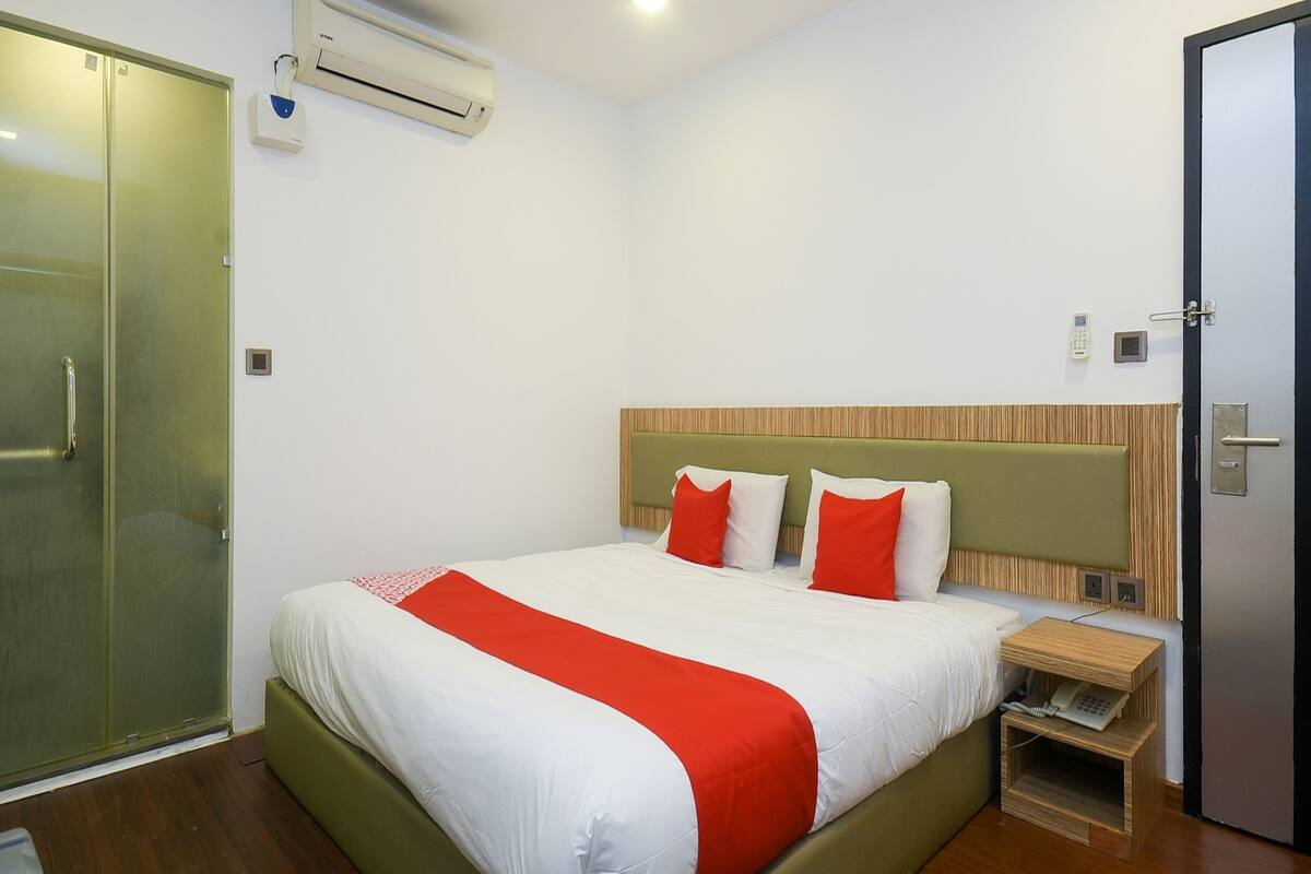Habitació d'hotel amb llit, taula de nit i armari.