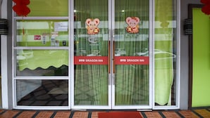 A hotel entrance with glass doors, a green curtain, and a red sign indicating the name "OYO Dragon Inn". - Hotel O agon Inn (Miri)