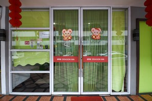 A hotel entrance with glass doors, a green curtain, and a red sign indicating the name "OYO Dragon Inn". - Hotel O agon Inn (Miri)
