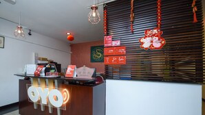 A reception desk with a sign reading "OYO" and a red decorative hanging with a golden emblem. - Hotel O agon Inn (Miri)