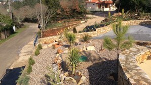 Una zona residenziale con un vialetto in pietra, uno stagno e una casa con tetto rosso.