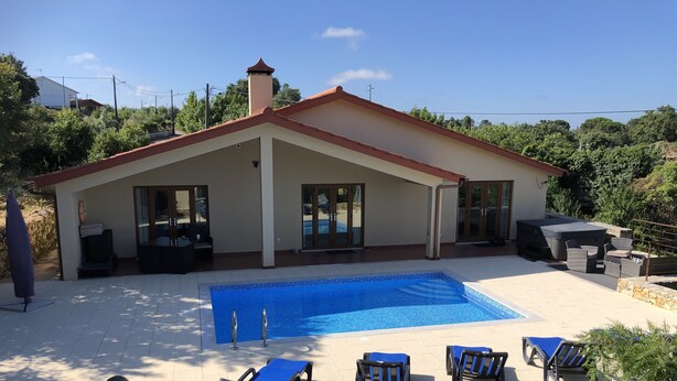 Una casa con piscina, muro in pietra e area relax all'aperto.