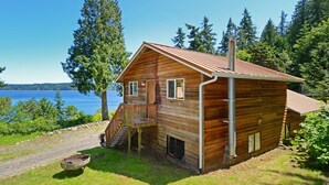 Une cabane en bois avec un toit en métal, une terrasse en bois et une vue sur un lac.