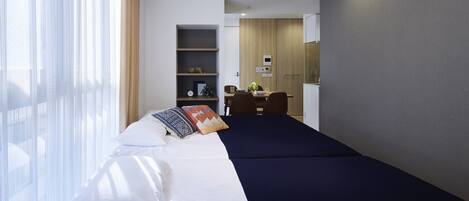 A hotel room with a bed, a desk, a wardrobe, and a small kitchenette.