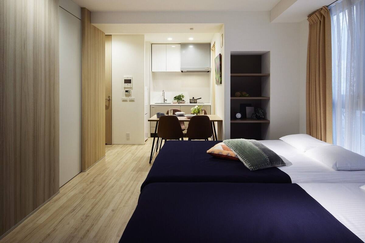 Une chambre d’hôtel avec un lit, un bureau et une kitchenette.