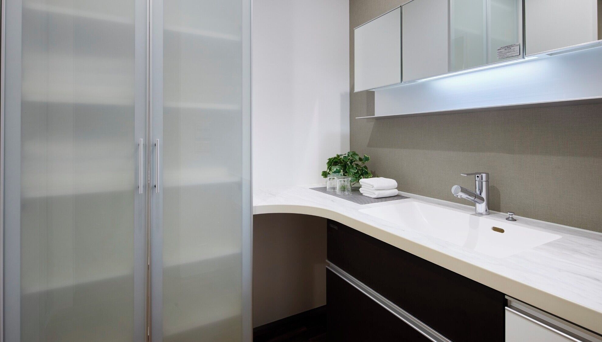 Een moderne badkamer met een witte wastafel, een wastafel, een spiegel en een kastje boven de spiegel.