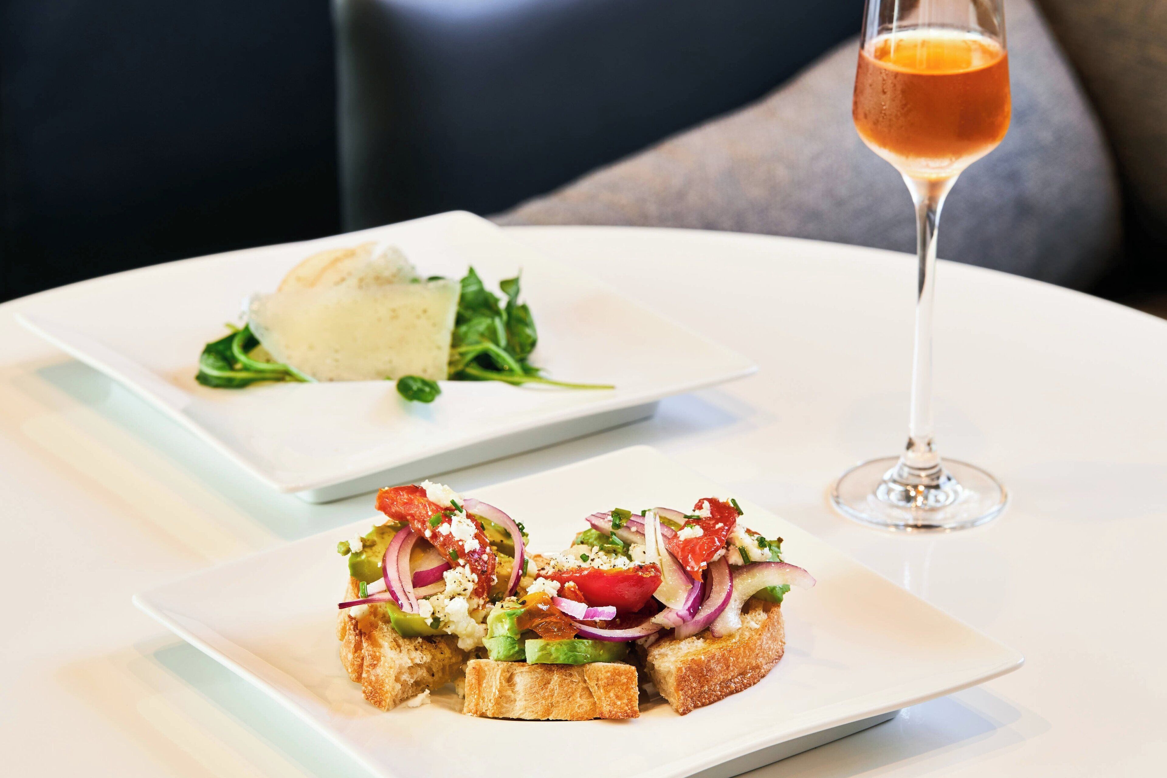 A white plate with a salad and a glass of orange juice on a table.