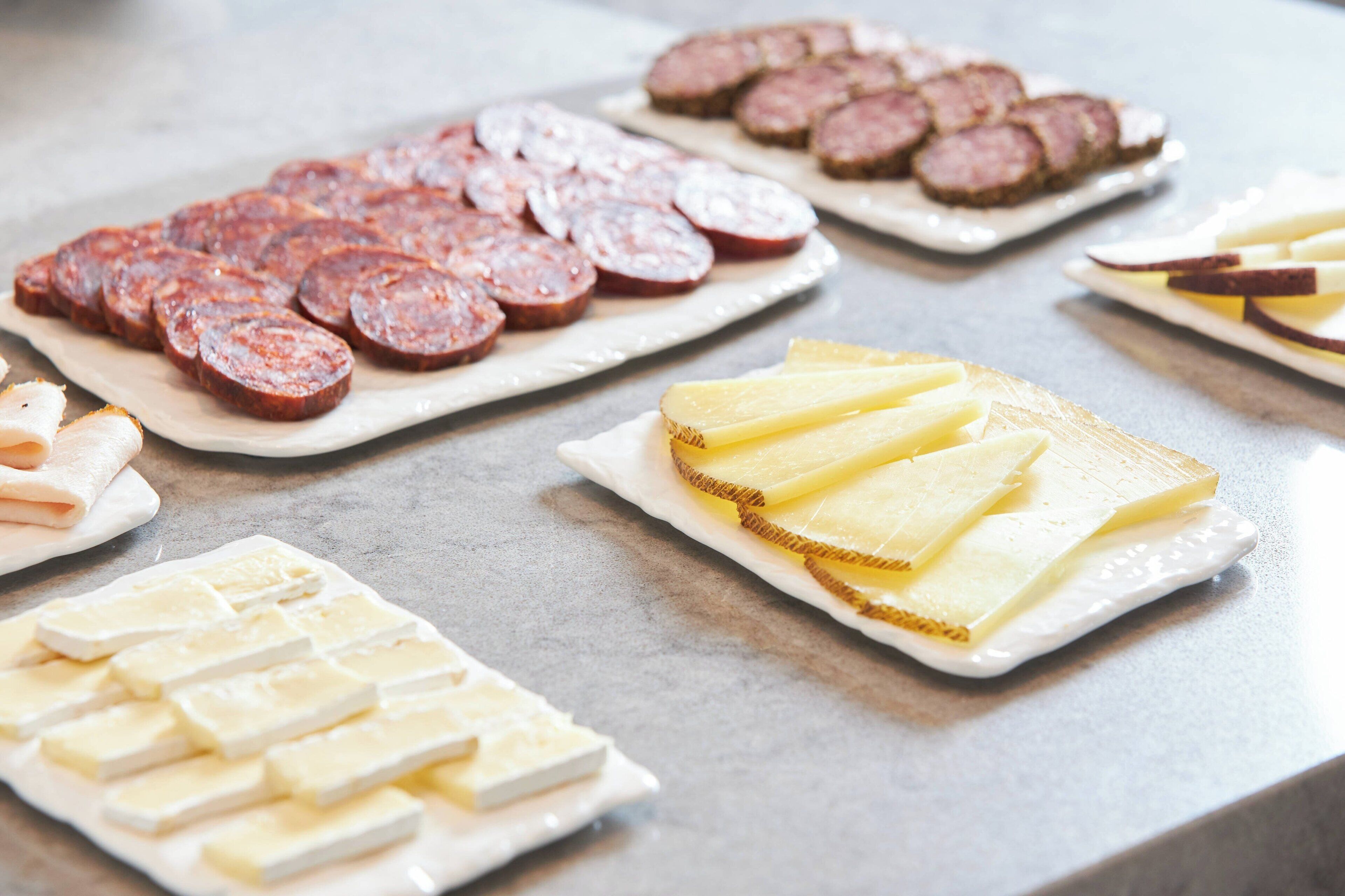 Buffet amb diferents aliments, incloent carn tallada i formatge.