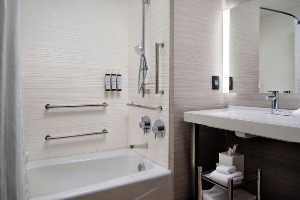 A modern bathroom with a bathtub, a shower, and a vanity with a mirror.