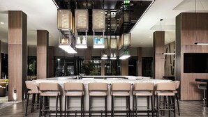 A modern kitchen with a central island, bar stools, pendant lighting, and wooden paneling. - AC Hotel by Marriott Dallas Frisco (Frisco)