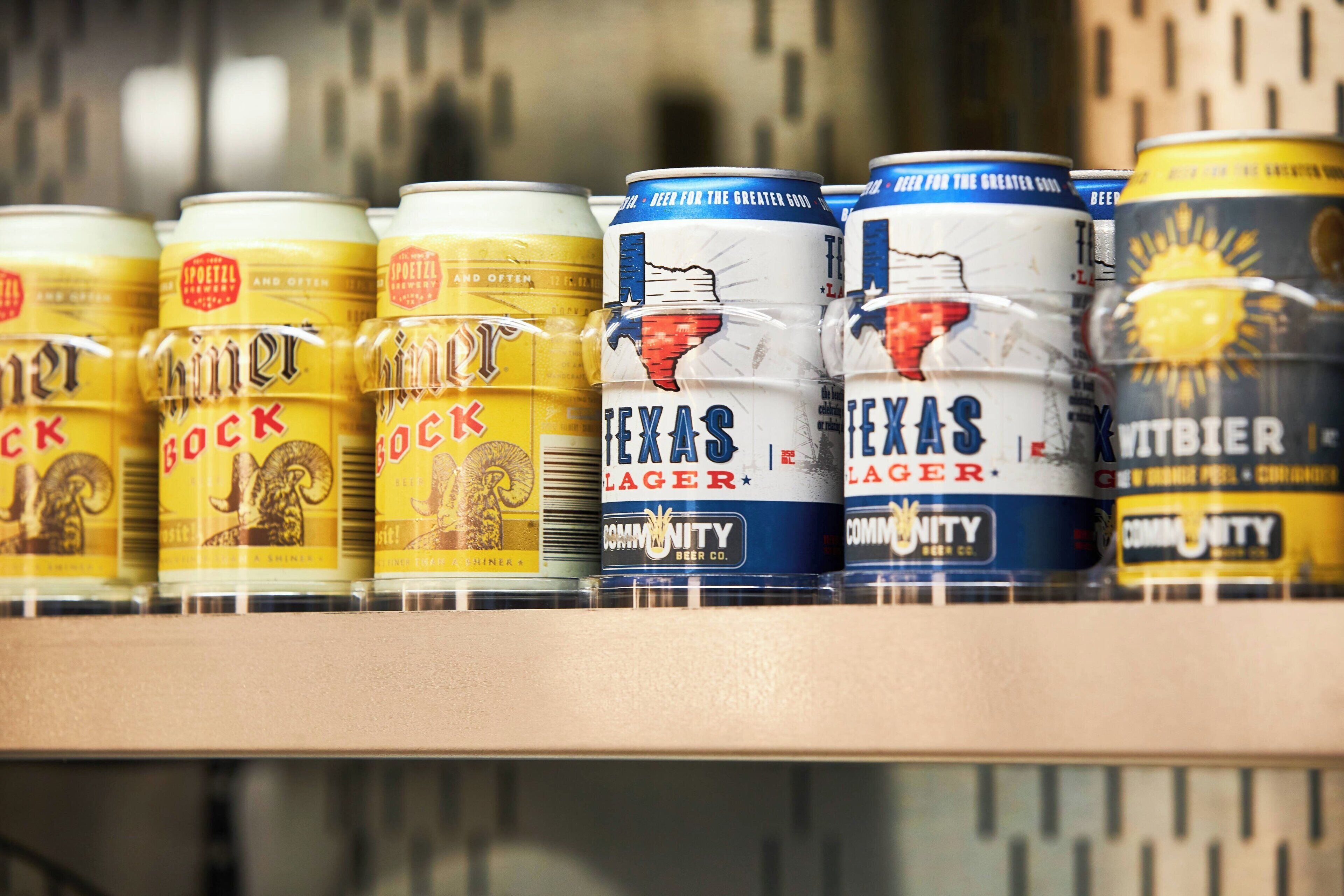 A row of beer cans on a shelf.