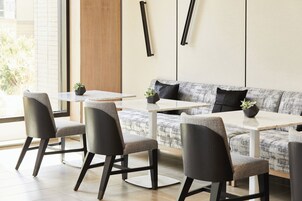 A modern dining area with a sofa and four chairs, a table, and a potted plant.