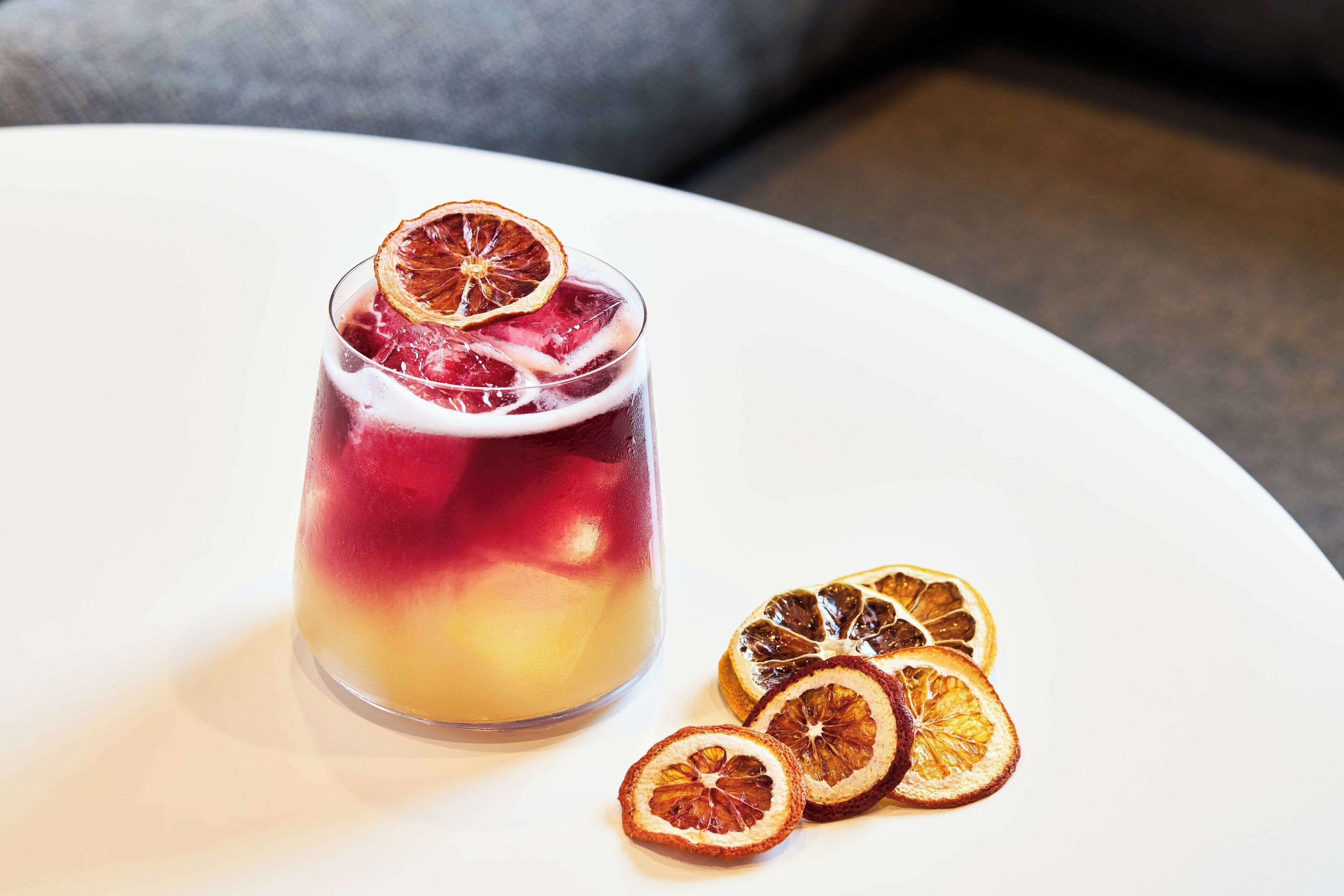 Un verre contenant une boisson à plusieurs couches, garnie de fruits secs, posé sur une assiette blanche.