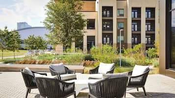 A patio with wicker furniture and a view of a modern building.