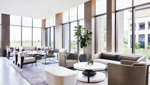 A spacious, modern lounge area with a large sofa set, a coffee table, and a potted plant. - AC Hotel by Marriott Dallas Frisco (Frisco)