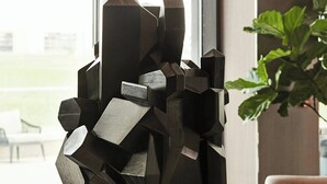A modern sculpture on a marble pedestal in a well-lit room with large windows, a plant, and a seating area. - AC Hotel by Marriott Dallas Frisco (Frisco)