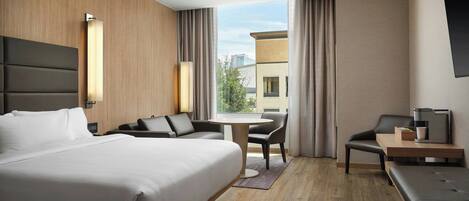 Ein modernes Hotelzimmer mit einem großen Bett, einem Schreibtisch, einem Stuhl und einem Sofa.