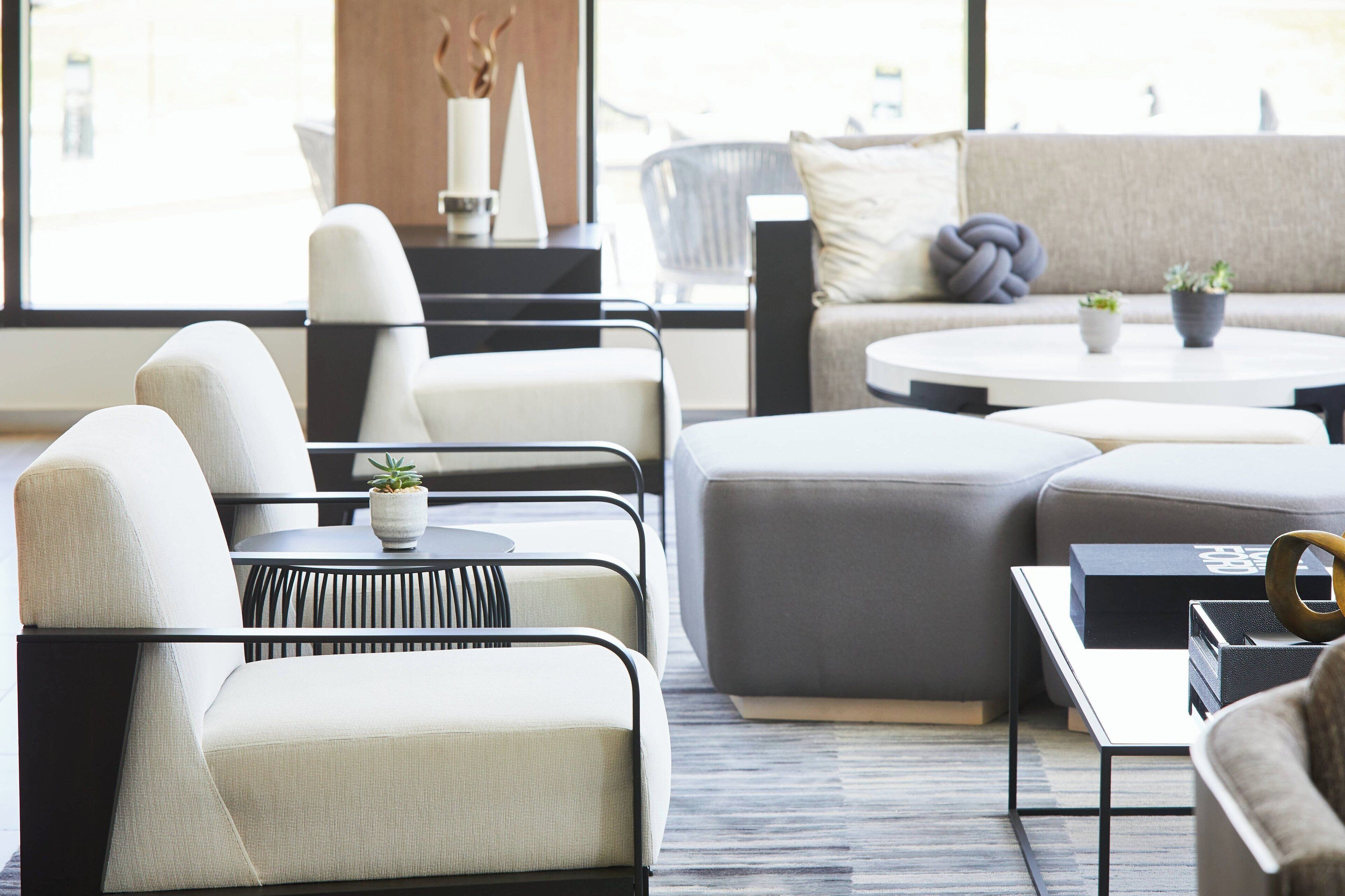 A modern living room with a sectional sofa, armchairs, a round coffee table, and a side table with decorative items.