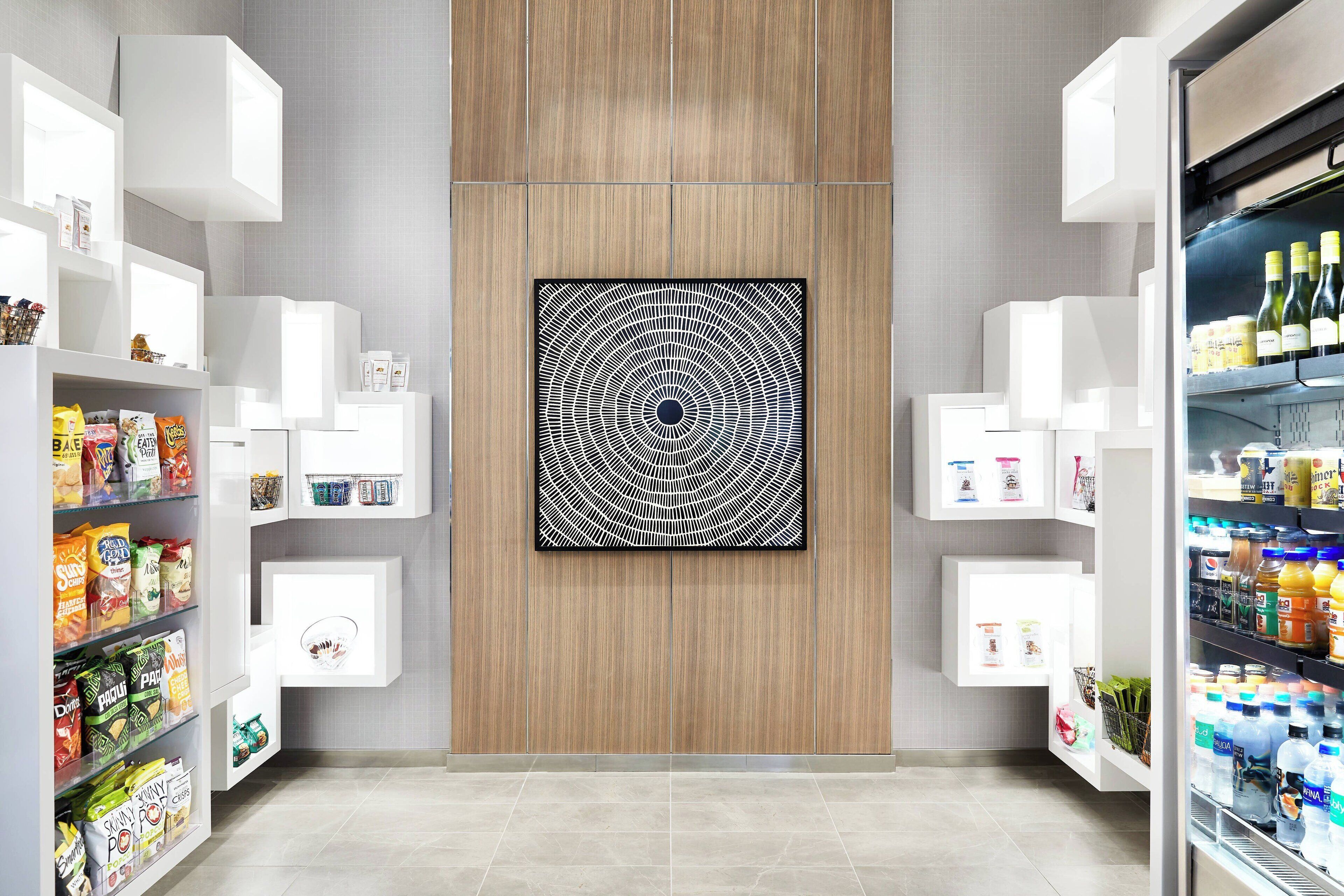Una cocina moderna con armarios blancos, un panel central de madera y una gran obra de arte blanco y negro.