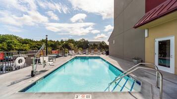 Een seizoensgebonden buitenzwembad, ligstoelen bij het zwembad