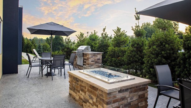 Un patio exterior con una barbacoa de piedra y zona de estar.