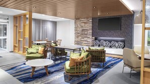 Un área de descanso moderna con una mesa de comedor, sofás y una pared decorativa de piedra.