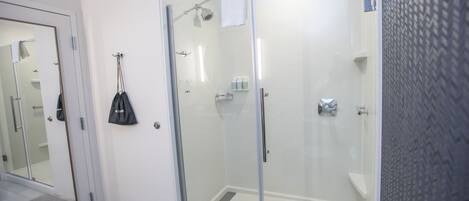 Une salle de bain moderne avec une douche à parois de verre, un lavabo blanc et un miroir.