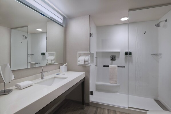Un baño moderno con un espejo grande, dos lavamanos, una ducha y un inodoro.