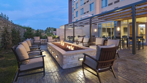 An outdoor patio with a fire pit, seating, and a building in the background.