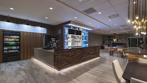 A modern bar area with a wooden counter, a beverage dispenser, and a menu board.
