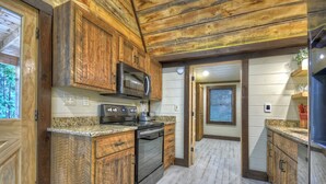 Une cuisine dotée de meubles en bois, d’un four à micro-ondes, d’une cuisinière et de plans de travail en granit.