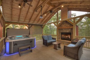 A wooden deck with a hot tub, two wicker sofas, a small table, and a stone fireplace. - OUTDOOR FIREPLACE, Outdoor Movies, king bed, PRIVATE hot tub, 1mile to downtown (Blue Ridge)