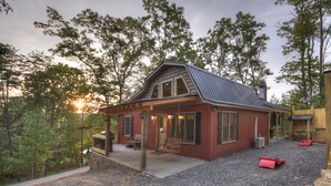 Une cabane rustique avec un toit en pente, un revêtement extérieur en bois et une véranda équipée de sièges.
