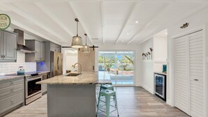 Una cocina moderna con una isla central, electrodomésticos de acero inoxidable y un amplio ventanal con vistas al exterior.