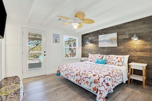 Quarto com cama, ventoinha no teto, parede de madeira e janela com persianas.