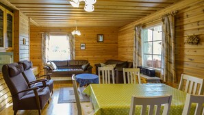 A cozy cabin interior with a dining area, a sofa, and a television. - Sieralahden lomakylä, mökki 2 by Interhome (Savonlinna)