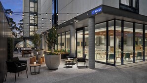 An outdoor seating area with tables and chairs, a large planter, and string lights. - Element by Marriott Melbourne Richmond (Burnley)