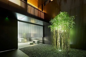 Um interior moderno com uma planta de bambu, um espaço de estar e uma grande janela.