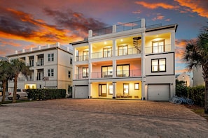Um edifício residencial de vários andares com varandas, garagem e entrada para carros.